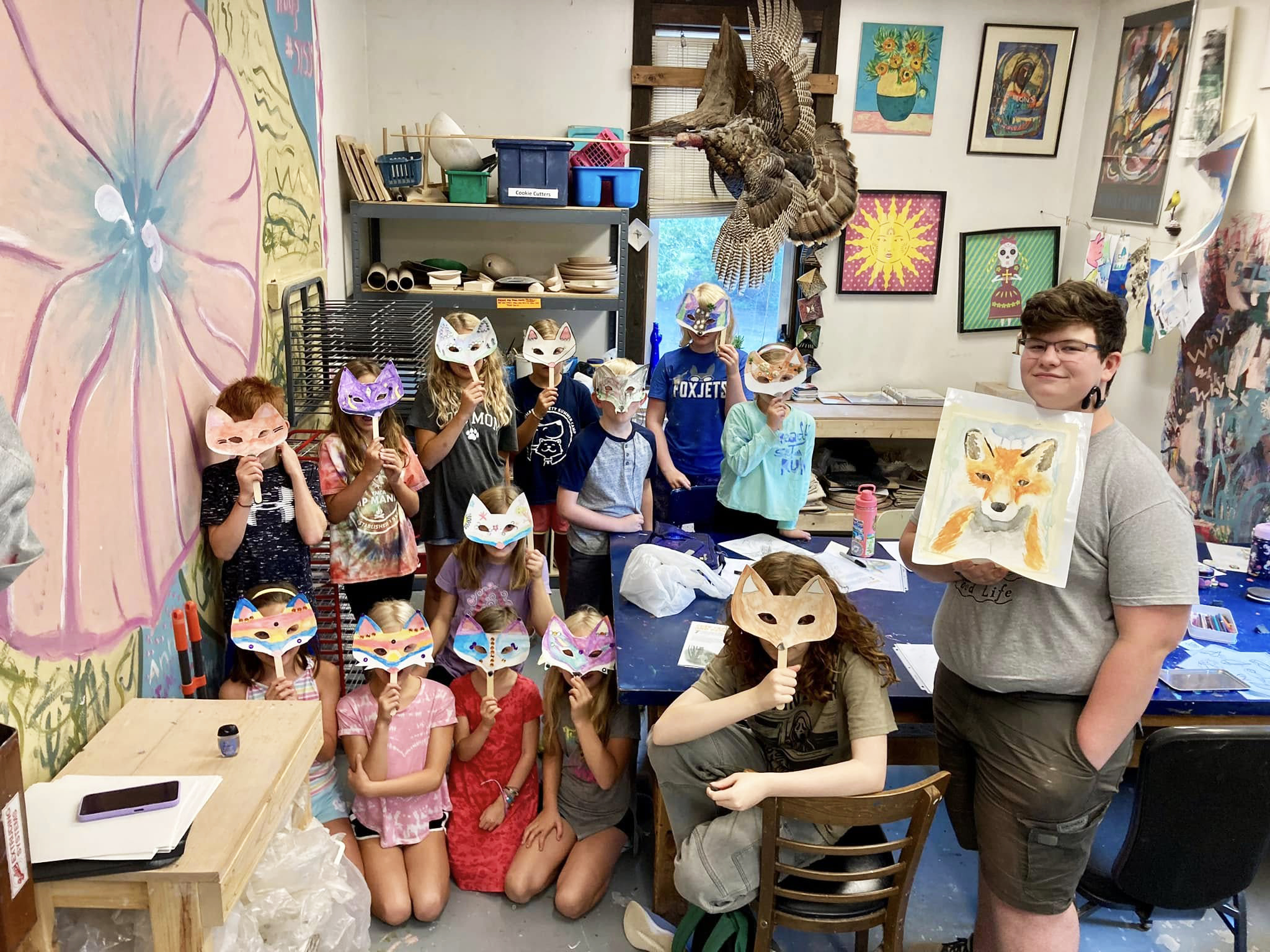 Students holding fox masks at The Blue Fox paint class